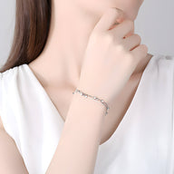Bracelet fin en argent sterling avec motif étoilé élégant porté au poignet féminin.