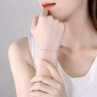 Bracelet fin en argent sterling avec deux étoiles entrelacées porté au poignet féminin.