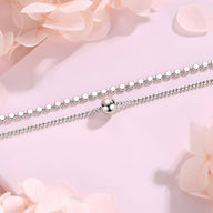 Bracelet double maille en argent sterling avec perle centrale lisse sur fond rose pâle.