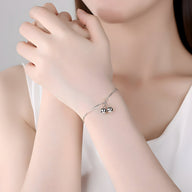 Bracelet fin en argent sterling avec deux perles rondes brillantes porté au poignet féminin.