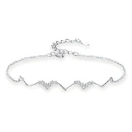 Bracelet fin en argent sterling avec motif symétrique ondulé et détails scintillants.