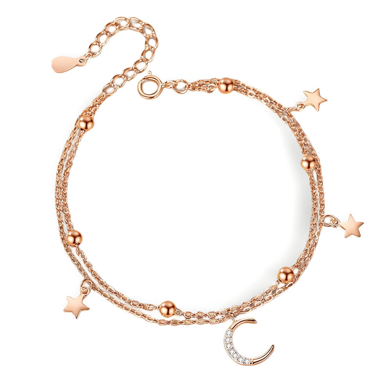 Bracelet en or rosé avec chaîne double, perles, lune et étoiles scintillantes en pendentifs.