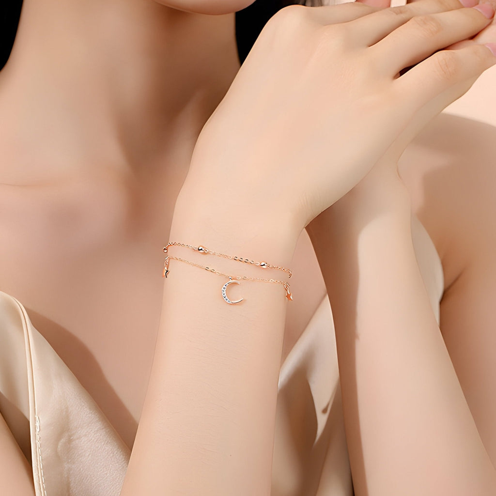 Bracelet en argent sterling or rosé avec pendentif lune scintillante sur poignet féminin.