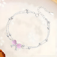 Bracelet en argent sterling à double chaîne fine avec petits boules et pendentif nœud ruban rose en cristal.