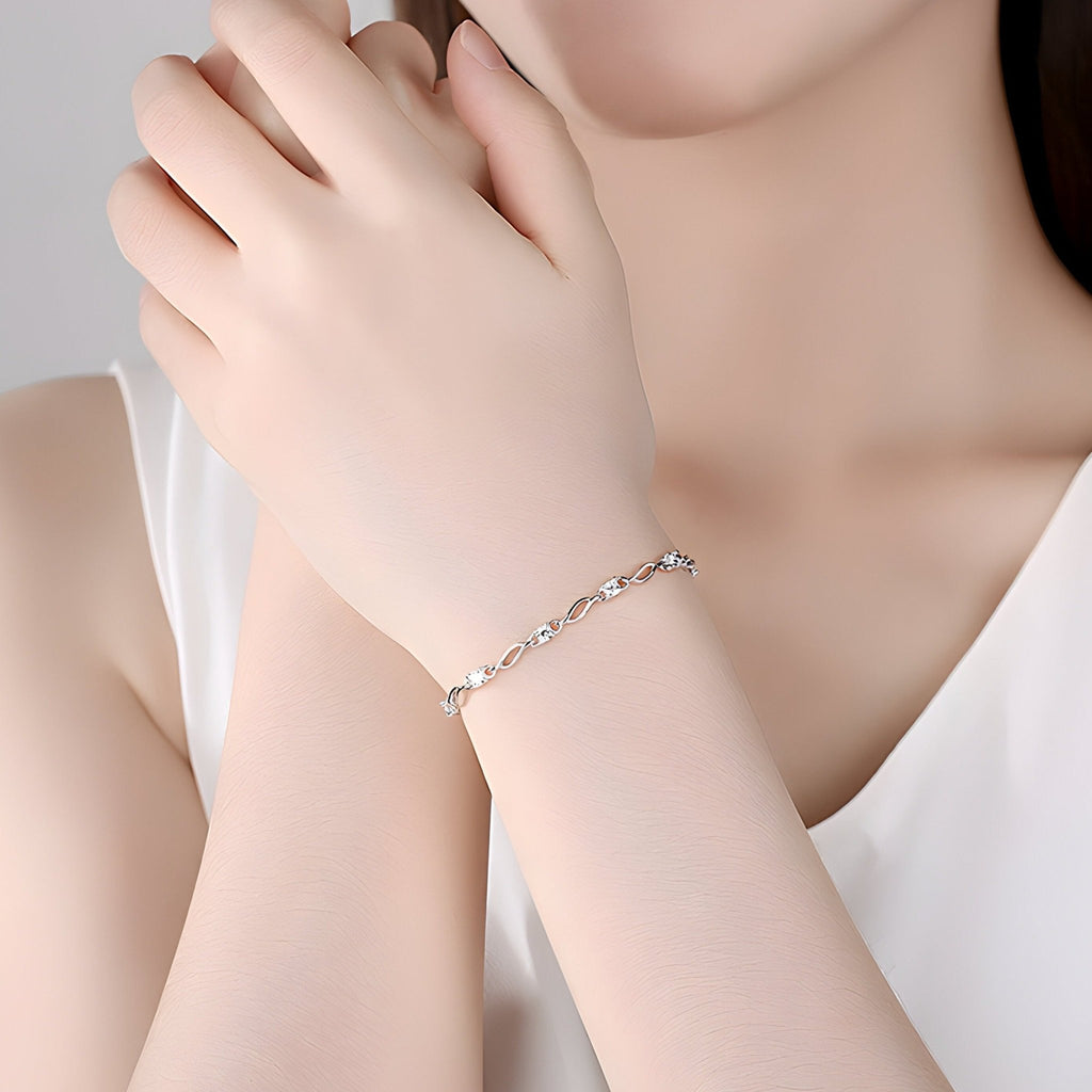 Bracelet ondulé en argent sterling, finition lisse et brillante, porté au poignet féminin.