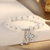 Bracelet en argent sterling avec perles blanches de jade et charm trèfle en strass éclatants.
