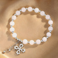 Bracelet en argent avec perles de jade blanc rosé et pendentif trèfle en argent scintillant.