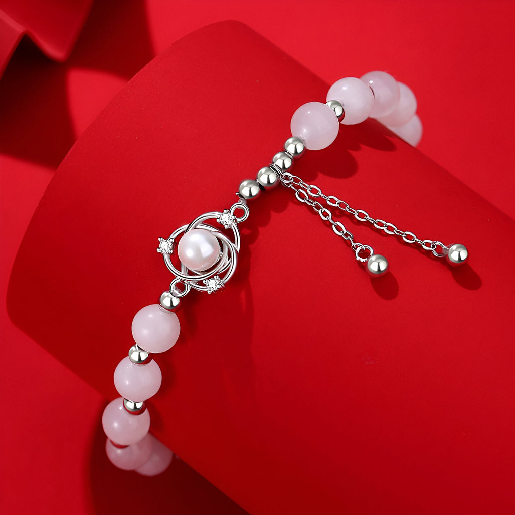 Bracelet en argent avec boules de jade rose et pendentif sphérique central élégant.