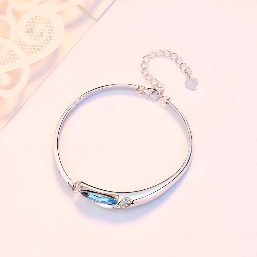 Bracelet fin en argent sterling avec pierre bleue facettée et détail de petits cristaux.