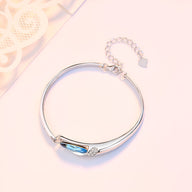 Bracelet fin en argent sterling avec pierre bleue facettée et détail de petits cristaux.