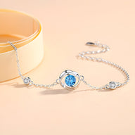 Bracelet en argent sterling avec zirconium bleu central et petits zirconiums clairs sur chaîne fine.