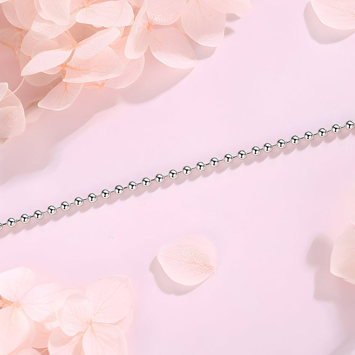 Bracelet fin en argent sterling avec petites perles arrondies sur fond rose pâle.
