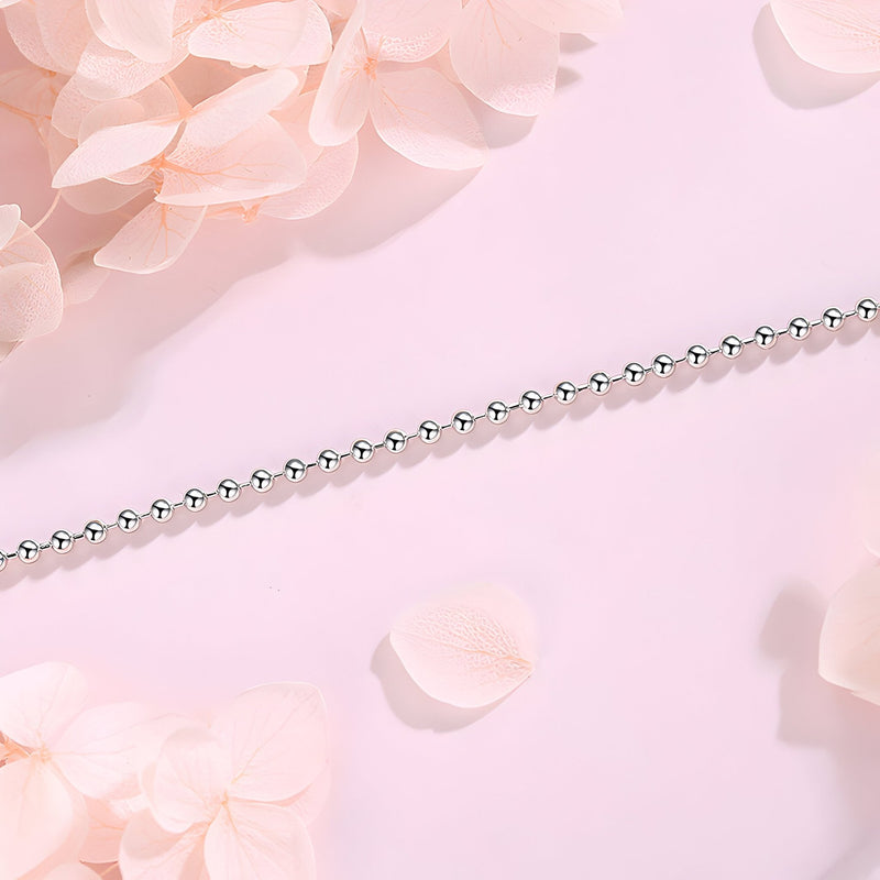 Bracelet fin en argent sterling avec petites perles arrondies sur fond rose pâle.