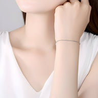 Bracelet fin en argent sterling avec petites perles rondes porté au poignet féminin.