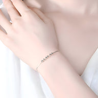 Bracelet fin en argent sterling avec petites perles rondes, porté au poignet féminin.