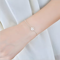 Bracelet fin en argent sterling avec pendentif smiley rond sur poignet féminin.