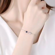 Bracelet fin en argent sterling avec pendentif soleil noir et nuage délicat, porté au poignet.