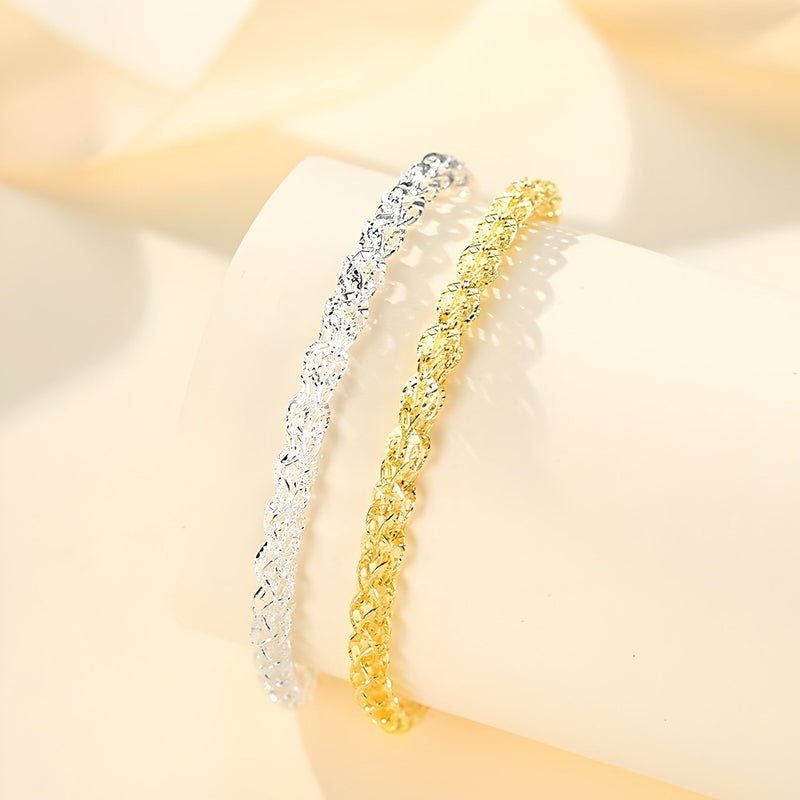 Bracelet torsadé en argent sterling pour femme à gauche et bracelet torsadé doré à droite sur fond clair.