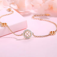 Bracelet en argent sterling orné de trèfles à quatre feuilles et d'un médaillon central ajouré, finition or rosé.