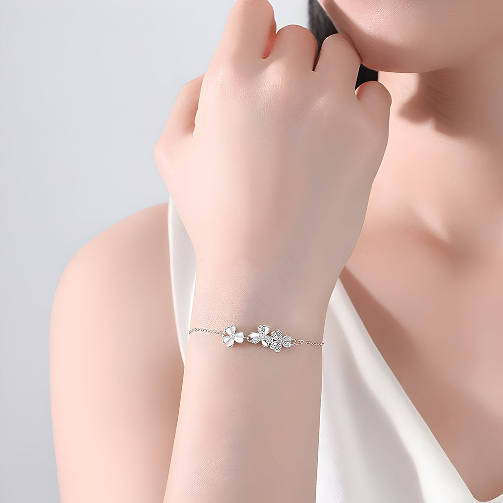 Bracelet fin en argent sterling avec pendentif trèfle à trois feuilles porté au poignet féminin.