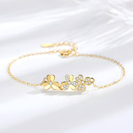 Bracelet fin en or avec pendentif trèfle à trois feuilles orné de petits cristaux brillants.