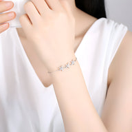 Bracelet fin en argent sterling avec trois étoiles délicates, porté au poignet féminin.