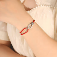 Bracelet rouge en cuir avec fer à cheval en argent sterling porté au poignet féminin.