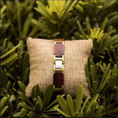 Bracelet homme en bois d'acajou marron avec maillons métalliques argent sur coussin beige.