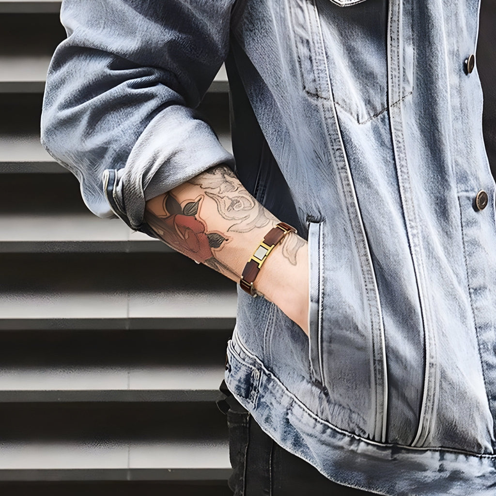 Bracelet en bois d'acajou marron avec détails argent portés sur poignet tatoué, style décontracté.