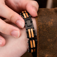 Bracelet en bois de noyer noir et marron avec maillons rectangulaires et fermoir métallique posé sur poignet masculin.