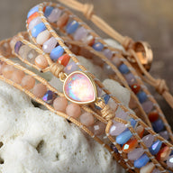 Bracelet multi-rangs en pierre d'opale multicolore et cuir beige avec perles cristallines et fermoir doré en forme de goutte.