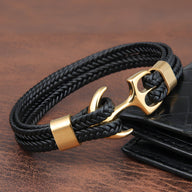Bracelet en cuir noir tressé avec motif ancre dorée et fermoir assorti, style marin élégant.