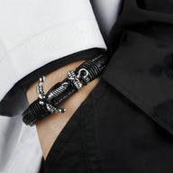 Bracelet en cuir noir avec motif ancre argentée entrelacée, style marin élégant.