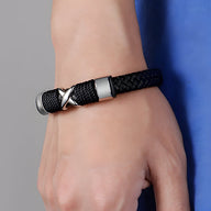 Bracelet en cuir noir tressé avec motif petite croix métallique, fermeture argentée.