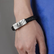 Bracelet noir en cuir tressé avec motif tête de mort ailée en métal argenté.