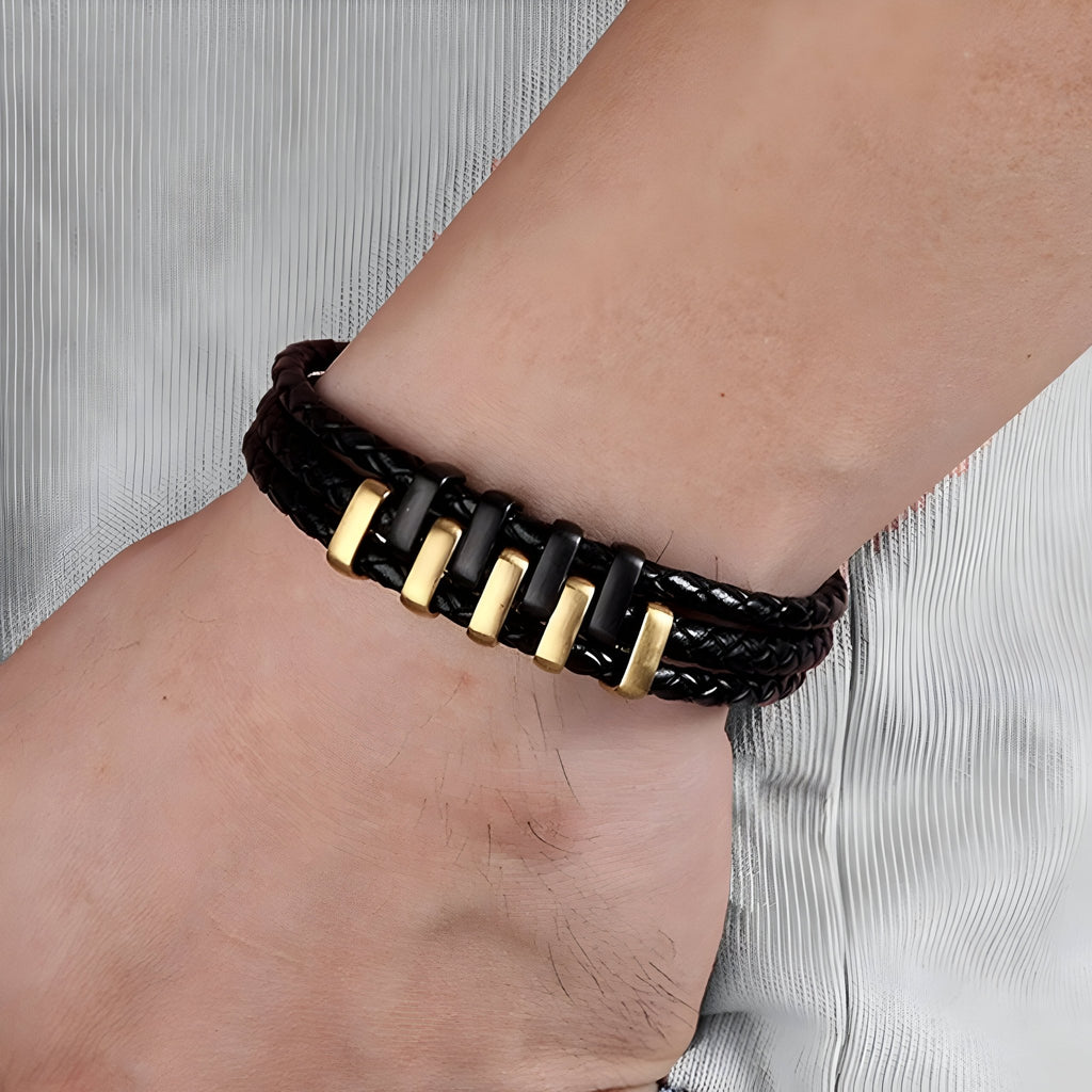Bracelet en cuir tressé noir avec cinq motifs métalliques dorés rectangulaires, style masculin.