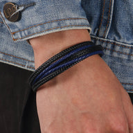 Bracelet multi-rangs en cuir noir et bleu, style tressé, porté au poignet homme.