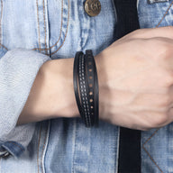 Bracelet multi-rangs noir en cuir ajouré au design simple et moderne porté au poignet.