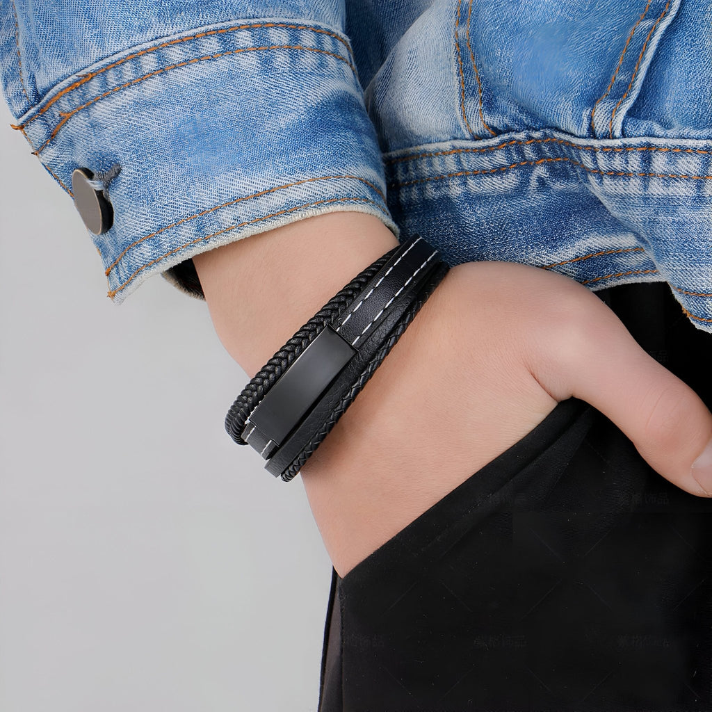 Bracelet en cuir noir multi-rangs avec coutures blanches porté au poignet avec veste en jean.