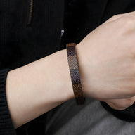 Bracelet fin en cuir marron à motif tressé porté au poignet homme.