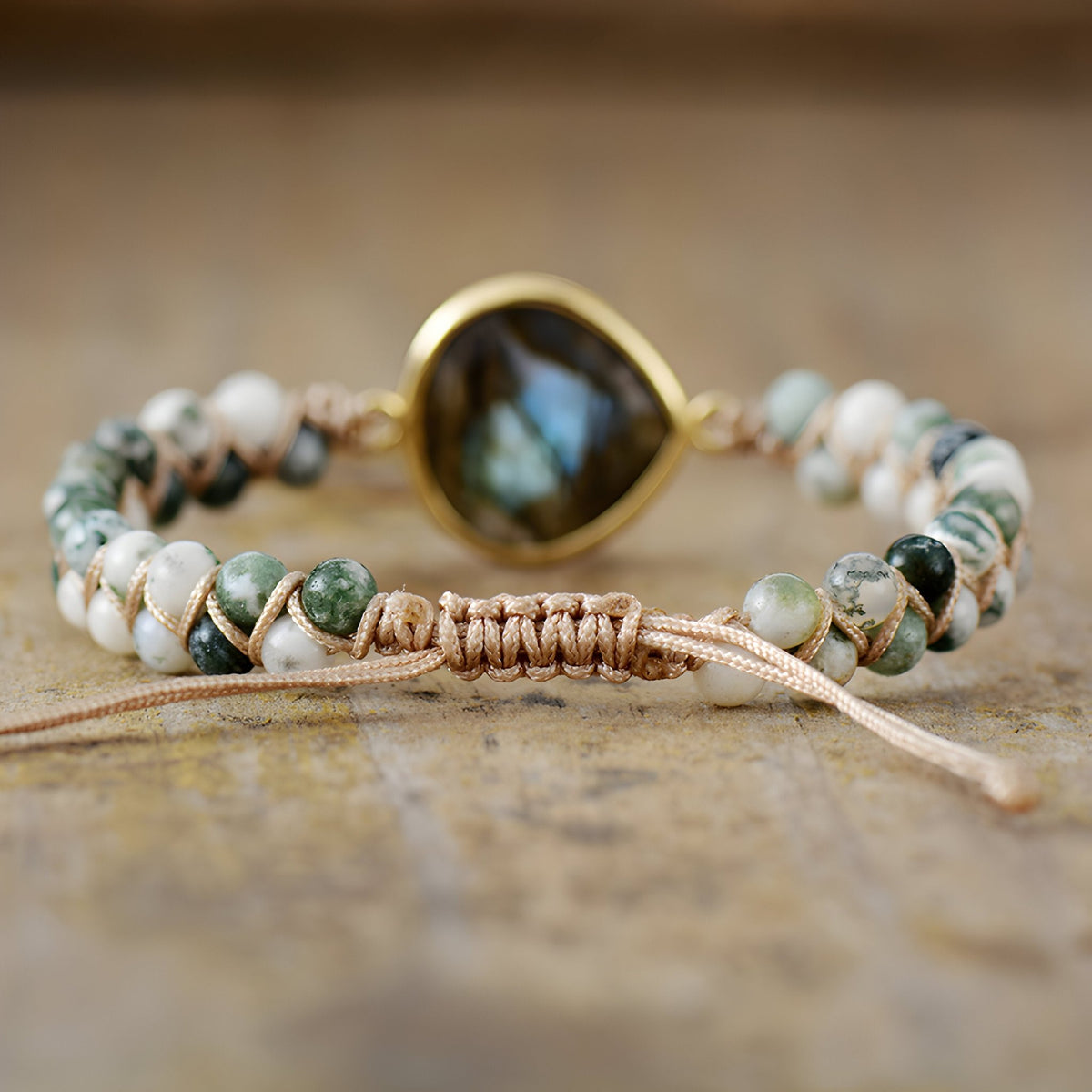 Bracelet femme pierres naturelles labradorite bleue centrale sertie or, perles blanches et vertes sur cordon beige tressé.