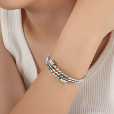 Bracelet jonc flexible en maille serpent argenté avec fermoir minimaliste porté au poignet.