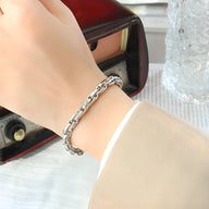 Bracelet en maille épaisse en titane couleur argent sur poignet féminin, style moderne élégant.