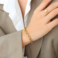 Bracelet en maille épaisse en titane plaqué or 18 carats porté au poignet, style élégant et moderne.