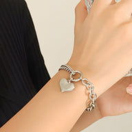 Bracelet gourmette en titane doré 18 carats avec pendentif cœur lisse, style Alva, porté au poignet.