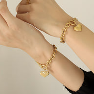 Bracelet en maille gourmette doré 18 carats avec pendentif cœur lisse porté au poignet.