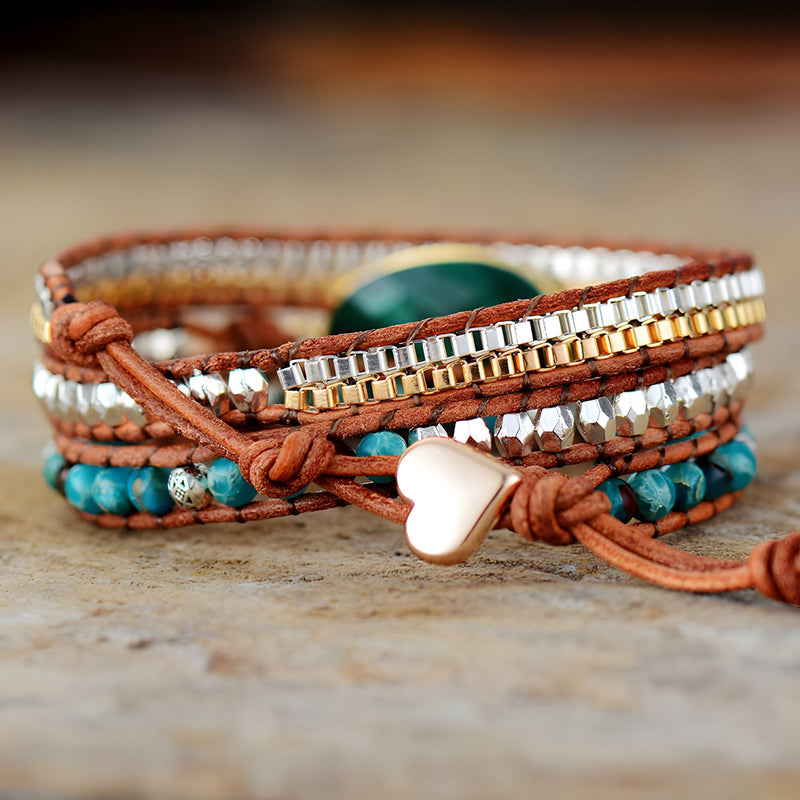 Bracelet multi-rangs en cuir marron avec perles de malachite verte, jaspe turquoise et détail cœur en métal rose doré.
