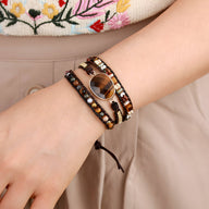 Bracelet multi-rangs en perles d'œil de tigre et jaspe marron porté au poignet féminin.