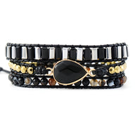 Bracelet multi-rangs noir en onyx, perles noires, cuivre doré et détail goutte centrale lisse.