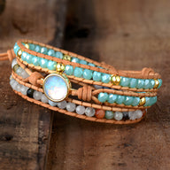 Bracelet multi-rangs en cuir avec perles turquoise, gris, blanc et or, ornement central en opale scintillante.